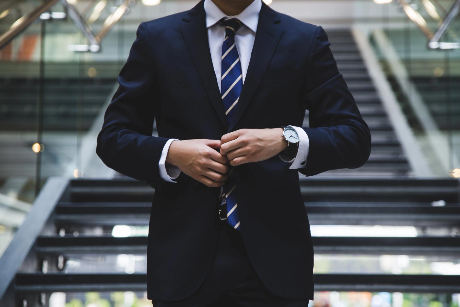A man buttoning up his blue suit jacket